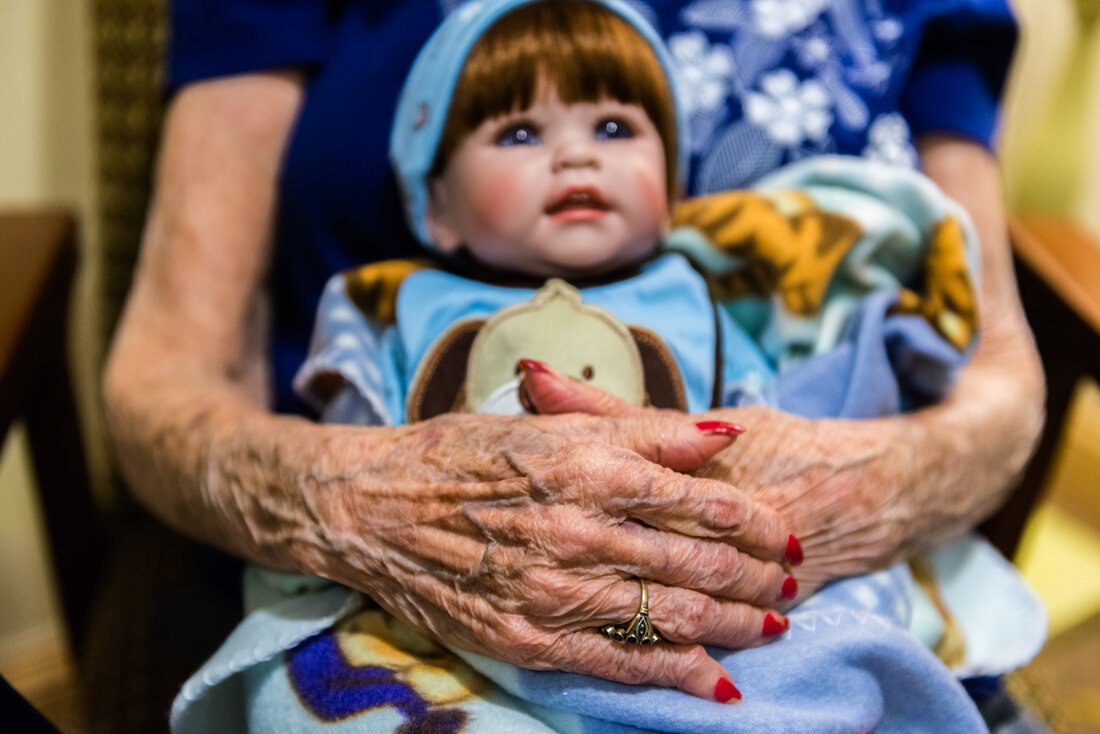 An older adult's hands resting on a realistic doll